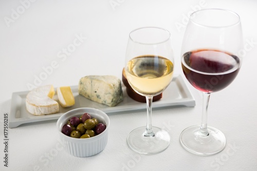 Close-up marinated olives with glasses of wine and cheese in