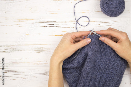 hand with the needles and a knitted cloth. on wooden white background photo