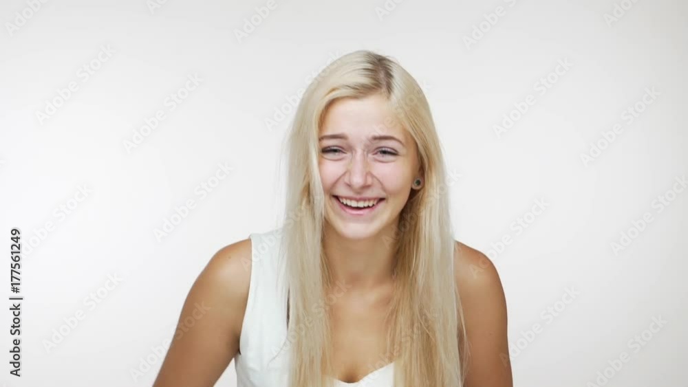 funny young joyful long-haired woman hysterically laughing covering her mouth with hands giggling feeling hot over white background slowmotion. Concept of emotions funny young joyful long-haired woman hysterically laughing covering her mouth with hands giggling feeling hot over white background slowmotion. Concept of emotions