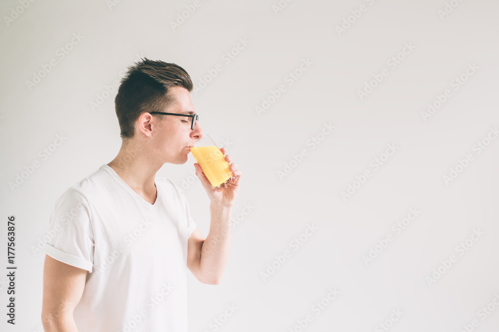 Happy man holding glass of orange juice isolated on white background. Nerd is wearing glasses. Happy man holding glass of orange juice isolated on white background. Nerd is wearing glasses.