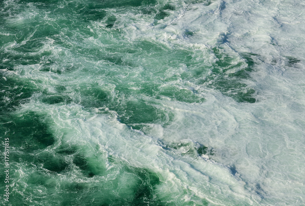 Water of the Rhine river just below the Rhine Falls in Switzerland, covered by foam produced by the waterfall