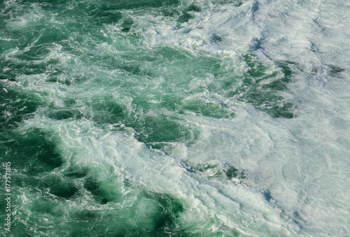 Water of the Rhine river just below the Rhine Falls in Switzerland, covered by foam produced by the waterfall