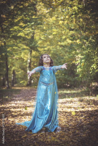 Happy girl in blue dress playing with leaves in the woods,selective focus