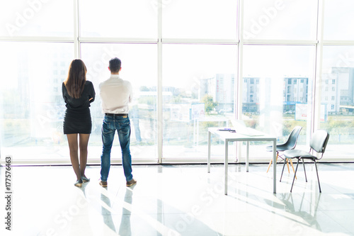 Office staff is discussing something by the window standing with their backs. Team work. photo