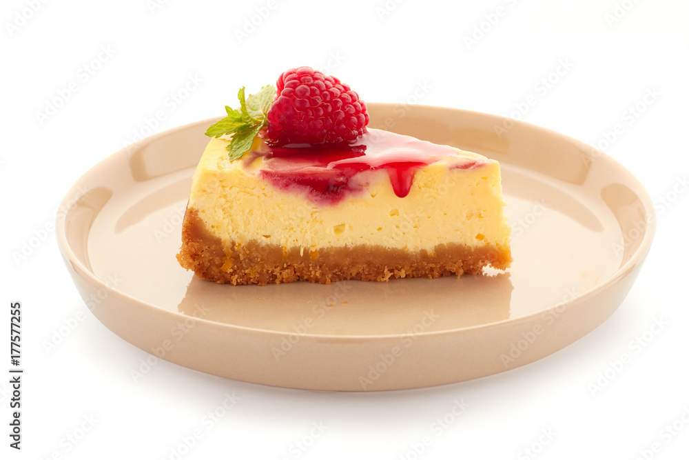 Piece of homemade cheesecake, decorated with raspberries and mint on plate over white Piece of homemade cheesecake, decorated with raspberries and mint on plate over white