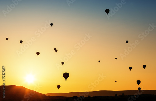 Balloons flying in the sky at sunrise.