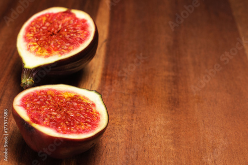 Photos a fig cut into two pieces on a wooden dark brown plate, place for text
