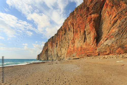 Paradise beach with large red rock descending to the sea