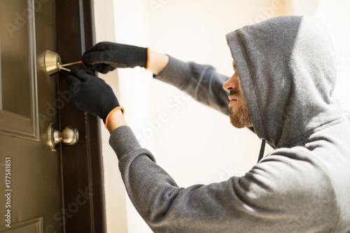 фотографія Burglar picking lock of a house and robbing