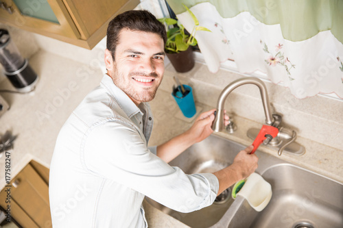 Happy handyman fixing a leaky faucet