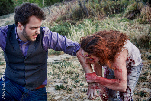 Photography A grotesque and bloody female zombie bites a man's arm
