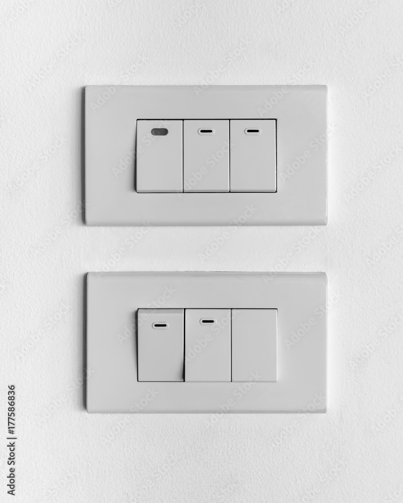 two white sets of triple lighting switchs on concrete wall two white sets of triple lighting switchs on concrete wall
