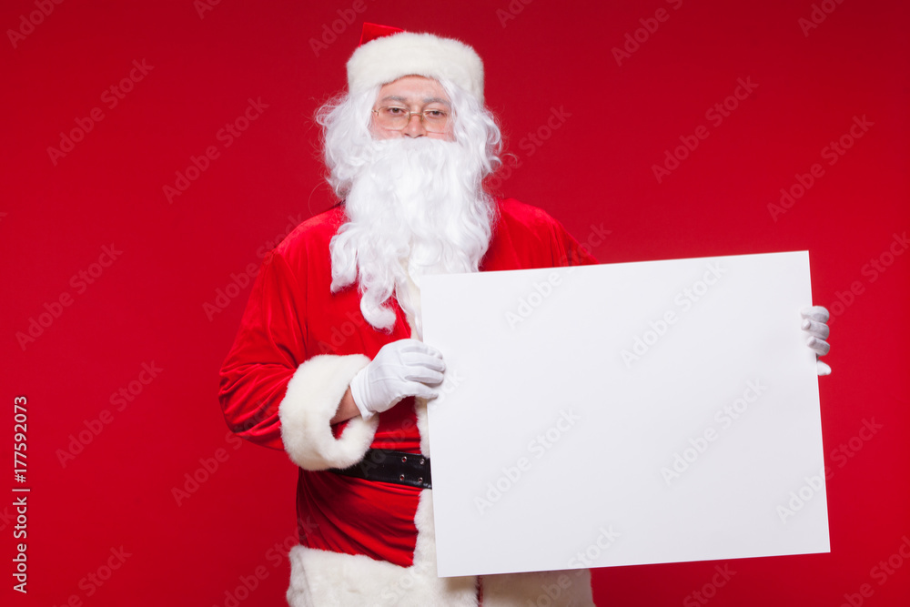 Santa Claus pointing in blank advertisement banner isolated on red background with copy space Santa Claus pointing in blank advertisement banner isolated on red background with copy space