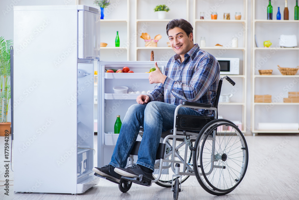 Young disabled injured man opening the fridge door Young disabled injured man opening the fridge door