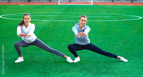 two young sports girls doing gymnastics in the morning on the green grass. open air, dawn, fitness, health, sports photo