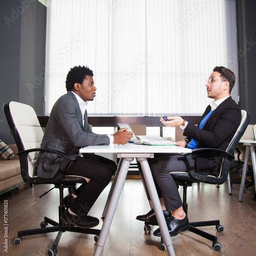 Two young businessmen, white desk, job interview, teamwork