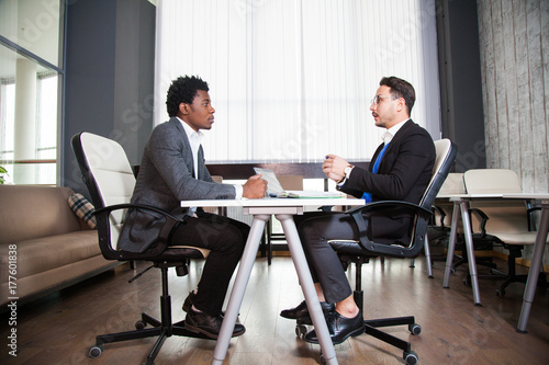 Two young businessmen, white desk, job interview, teamwork