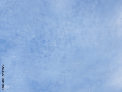 Pale light blue sky with small white clouds background, with consistently spreading transparent 