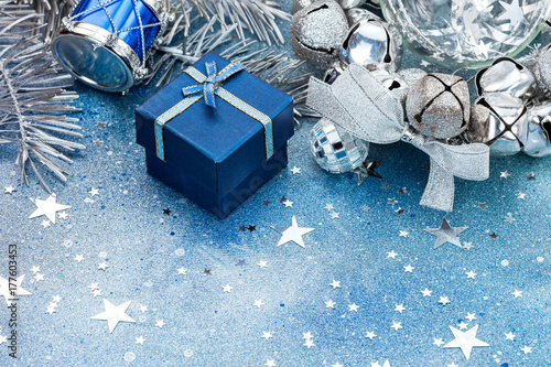 christmas tree decorations on blue sparkling background. silver balls, drum and blue small gift box.