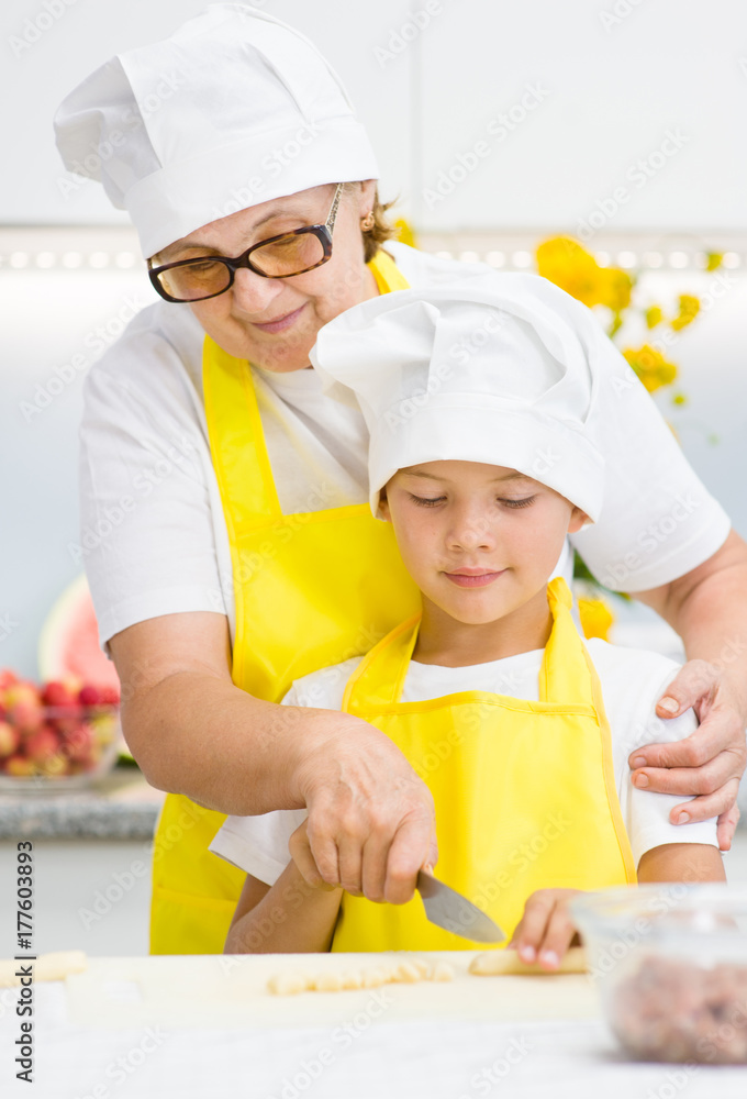 Grandmother teaches her grandson how to cook food in the kitchen Grandmother teaches her grandson how to cook food in the kitchen