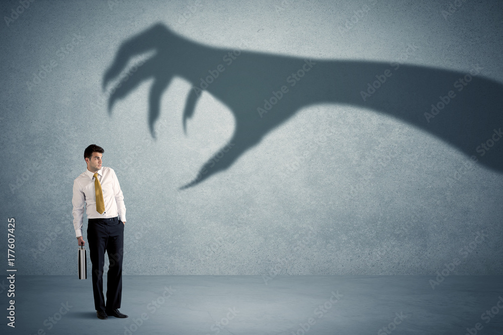Obraz premium Business person afraid of a big monster claw shadow concept