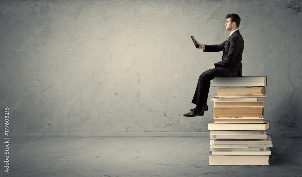 Man with laptop sitting on books Man with laptop sitting on books