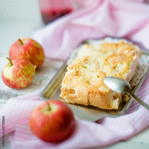 A fresh baked apple pie and a cut piece of pie are sprinkled with powdered sugar, close-up view
