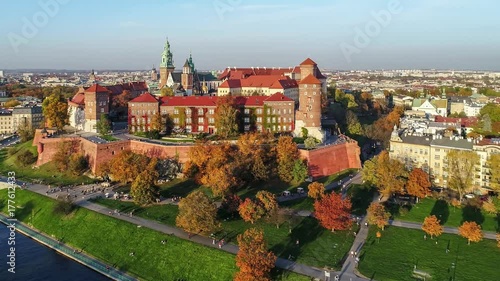 Krakow, Poland. Wawel royal Castle and Cathedral, Vistula River, park, promenade and walking people. Aerial 4K video in fall in sunset light