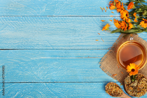 Calendula tea with fresh and dried flowers on blue wooden background with copy space for your text. Top view