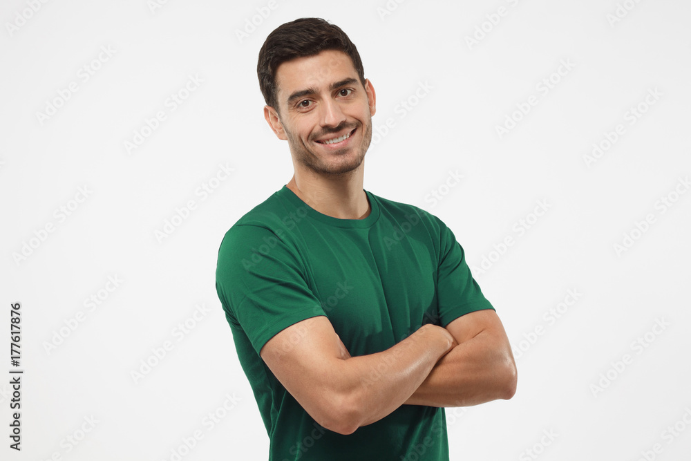 Portrait of attractive young sporty male in green t-shirt standing with crossed arms isolated on gray background. Fitness or crossfit trainer Portrait of attractive young sporty male in green t-shirt standing with crossed arms isolated on gray background. Fitness or crossfit trainer