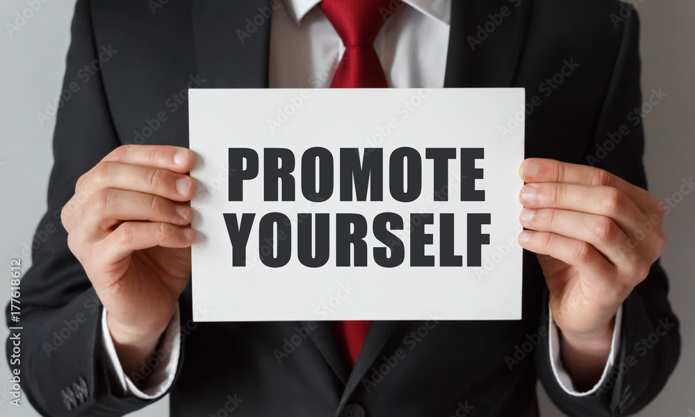 Businessman holding a card with text Promote Yourself Businessman holding a card with text Promote Yourself