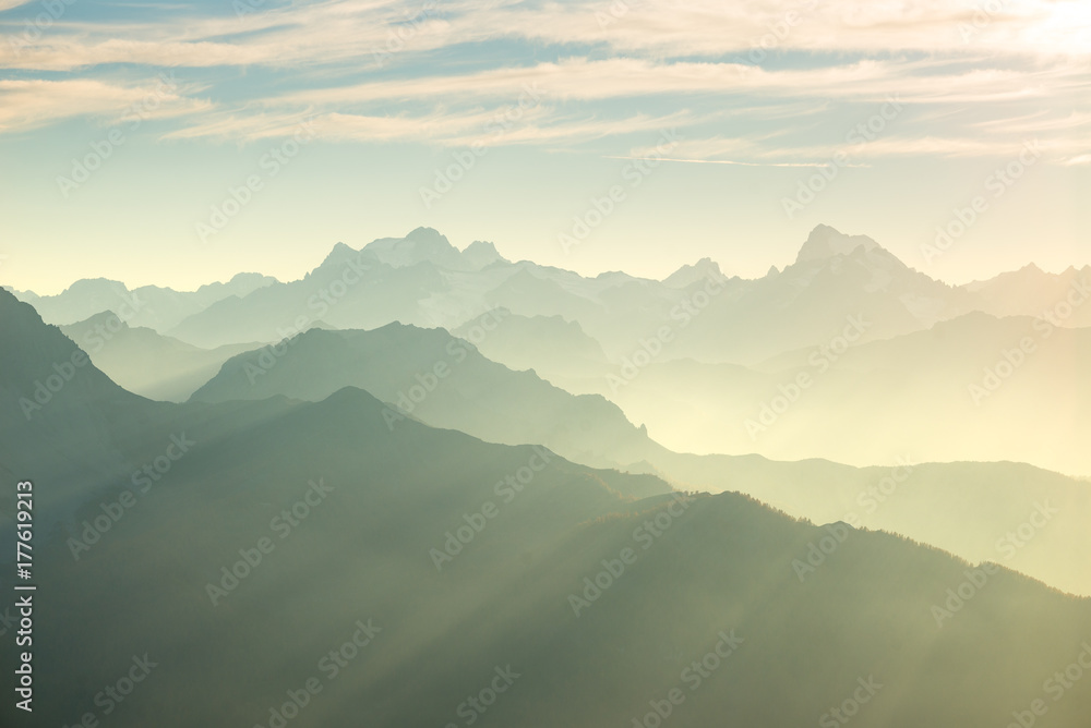 The Alps in soft backlight. Toned mountain range of the Massif des Ecrins National Park, France, arising higher than 4000 m altitude from the alpine arc. Telephoto view at sunset.