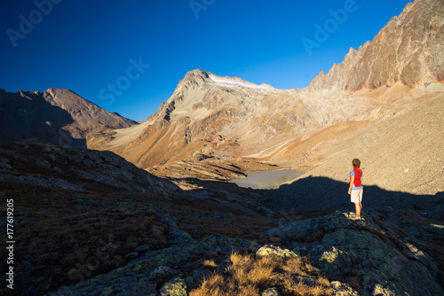 One person looking at view high up on the Alps. Expasive landscape, idyllic view at sunset. Rear view.
