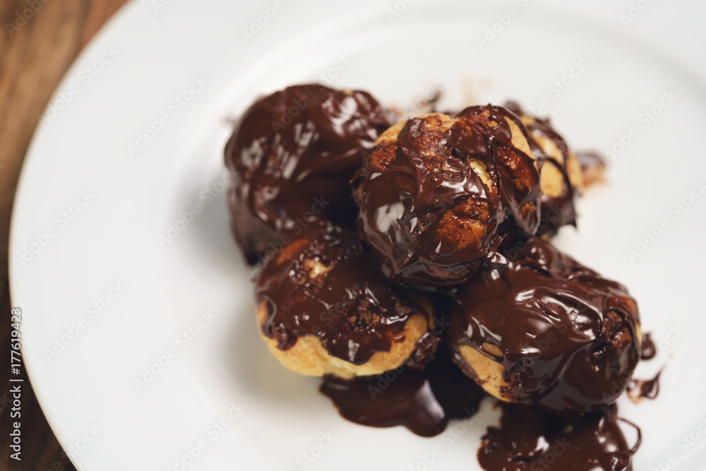 profiteroles covered with black chocolate on plate closeup