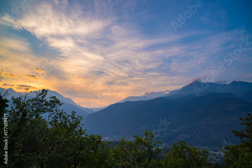 The Italian Alps at sunset. Summer colorful sky over the majestic mountain peaks  woodland and green valleys.