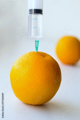 Photo of an injection into an orange on a light background