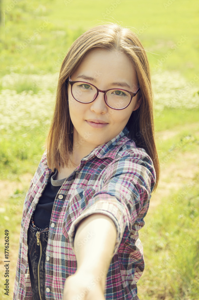 Pretty asian woman taking a selfie at grassy meadow. Pretty asian woman taking a selfie at grassy meadow.