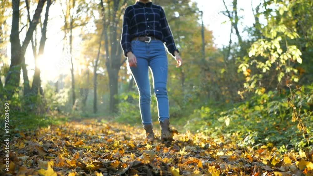 Legs of woman walking in autumn park on sunny day Legs of woman walking in autumn park on sunny day