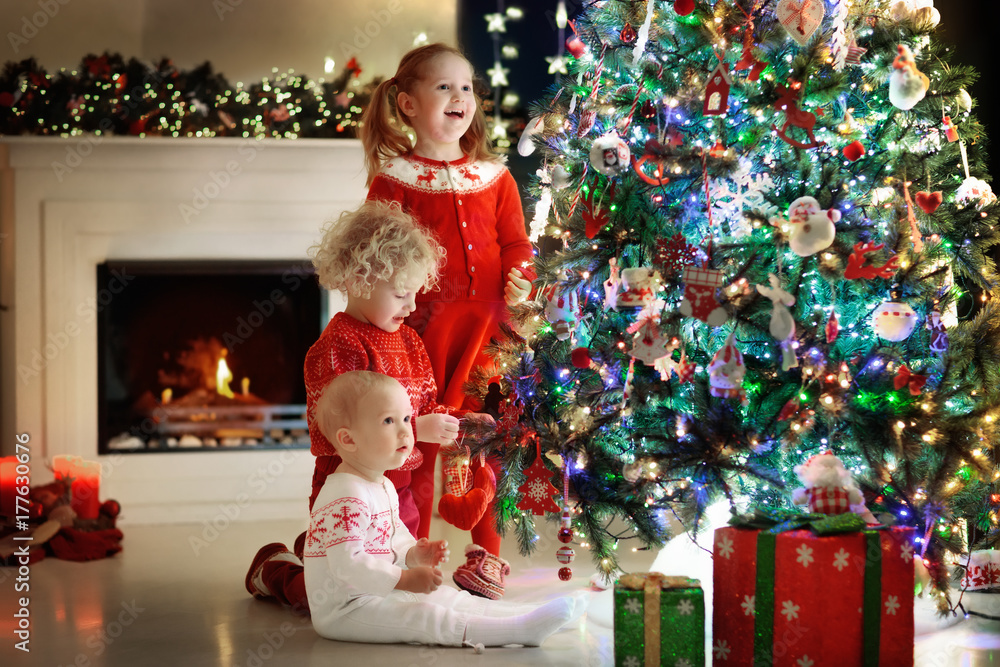 Children at Christmas tree. Kids at fireplace on Xmas eve