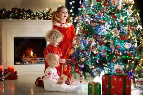 Children at Christmas tree. Kids at fireplace on Xmas eve