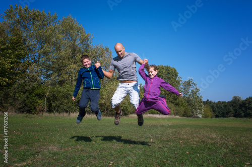 A family are jumping in the park at sunny day.