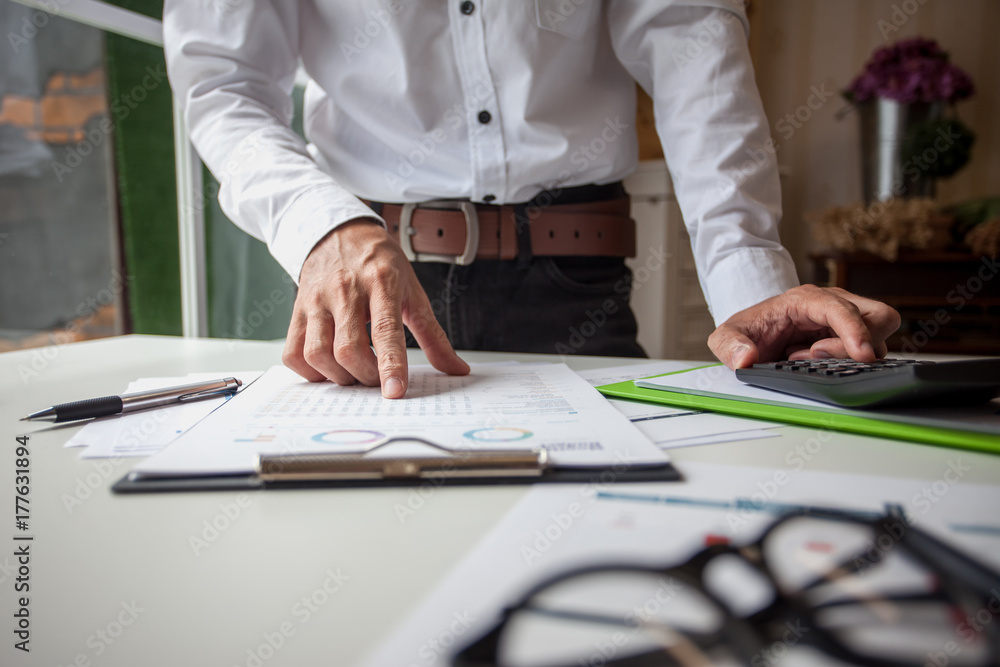 Business man working at office with calculator and documents on his desk Business man working at office with calculator and documents on his desk