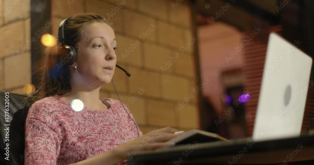 woman using laptop and headset communicating while sitting in cafe. woman using laptop and headset communicating while sitting in cafe.