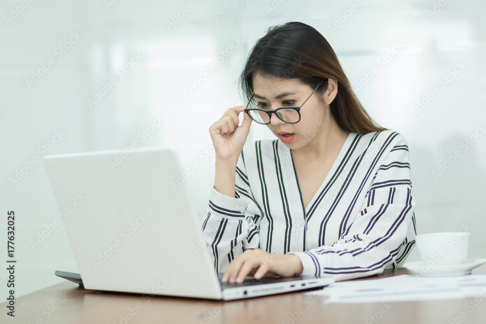 Young business woman working on laptop in office. Young business woman working on laptop in office.