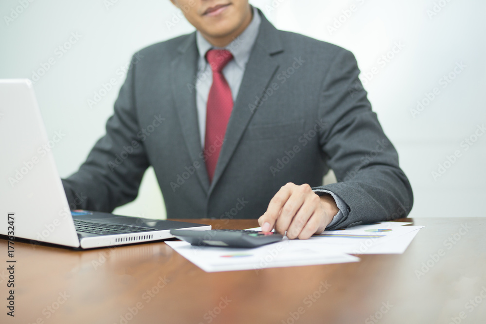 Selective focus Young business man working on laptop and calculator in office. Selective focus Young business man working on laptop and calculator in office.