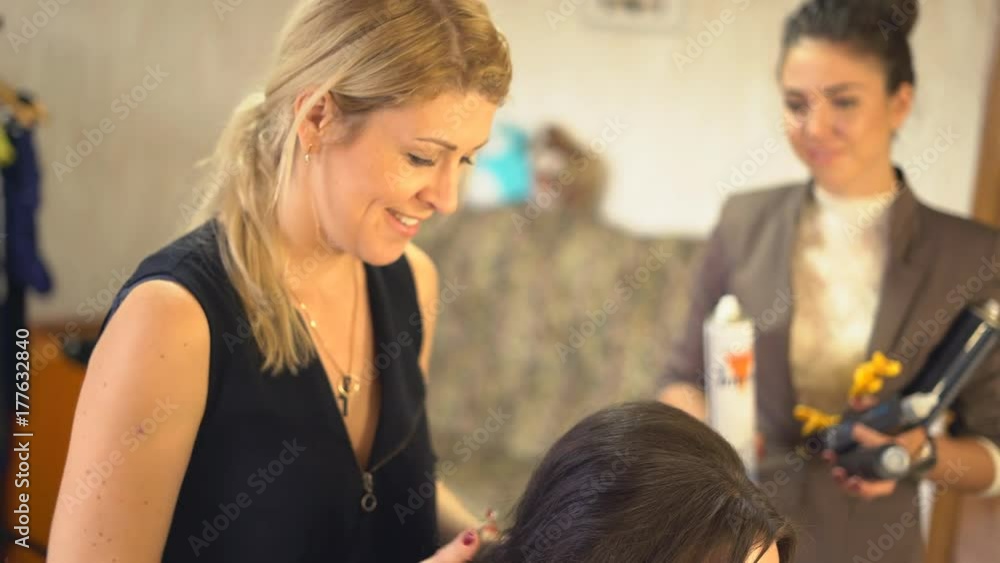 hair styling in the beauty salon. A professional hair stylist makes a haircut for the model with a comb. A woman is sitting in a chair in a beauty salon. young attractive brunette preparing for the hair styling in the beauty salon. A professional hair stylist makes a haircut for the model with a comb. A woman is sitting in a chair in a beauty salon. young attractive brunette preparing for the