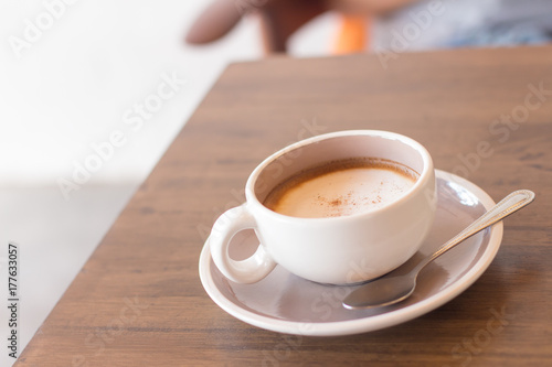 Coffee in a cup on a wooden table with a spoon