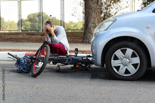 A woman holding her head near a traffic accident between electric ebike and car © studio4pic