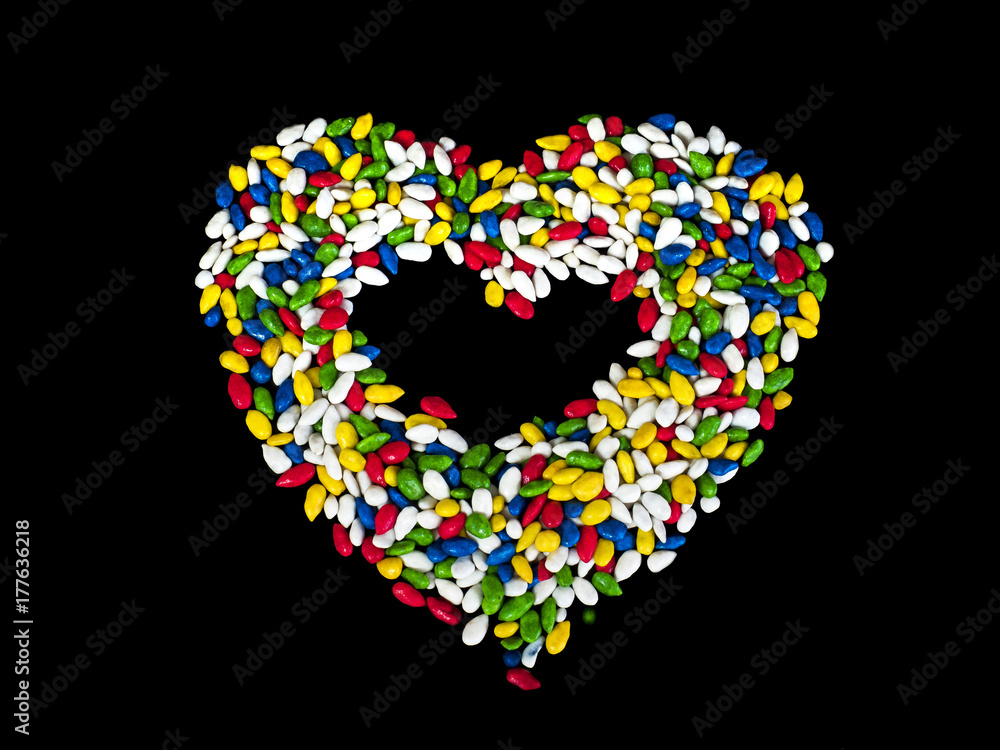 Sweets in heart shaped. Sunflower seeds in color glaze. Вlack background