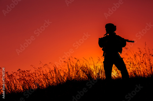 military soldier with weapons at sunset. shot, holding gun, colorful sky. military concept. © kaninstudio